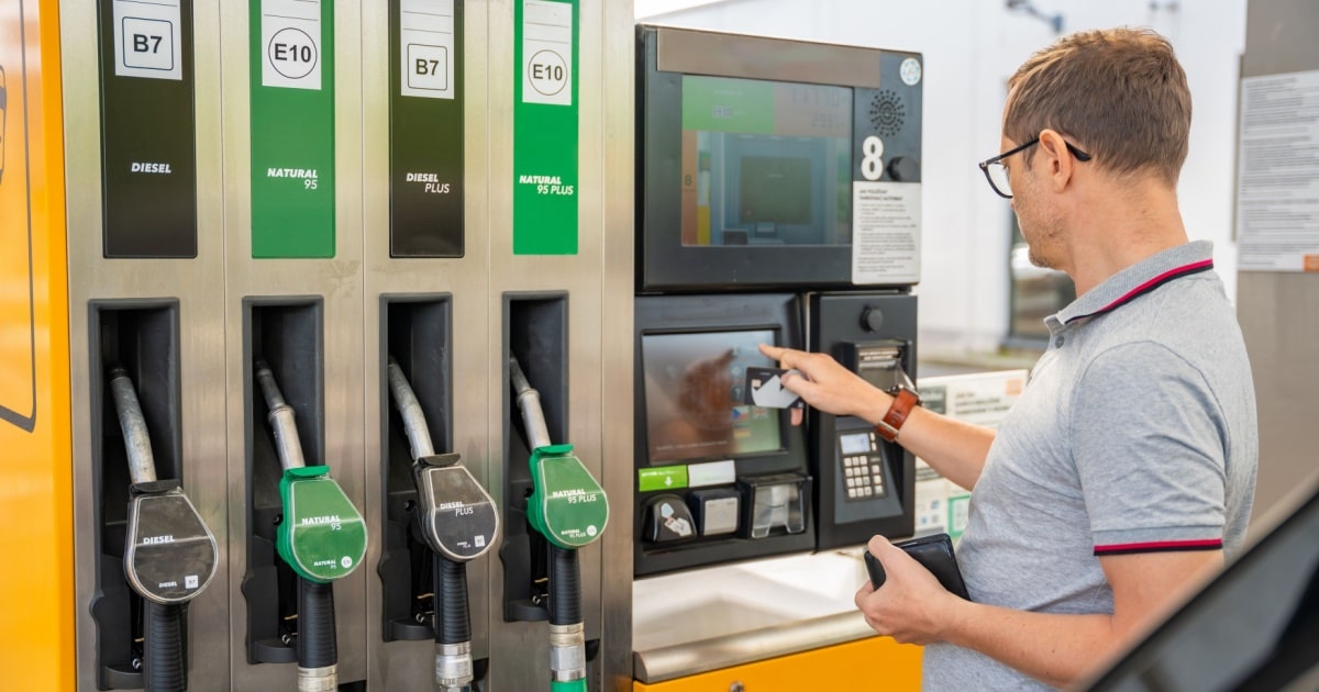 Un homme paie le plein de carburant de sa voiture à l'aide d'une carte carburant.